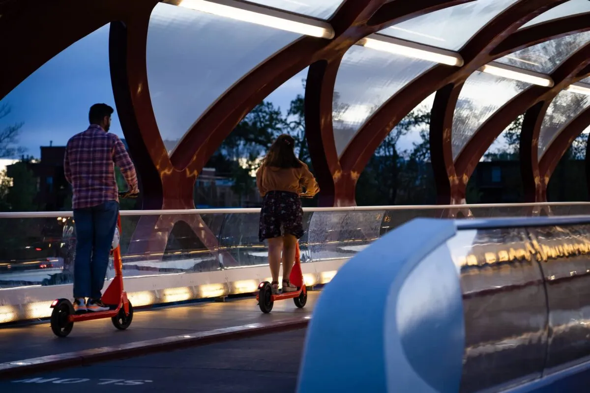 Calgary Alberta Canada, Two people in motion ride e-scooters across the Peace Bridge at night in a popular downtown district during dusk. — Depositphotos