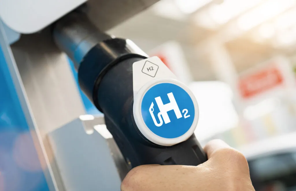 Man hold a fuel dispenser with hydrogen logo on gas station h2, Depositphotos