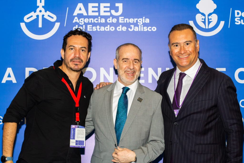 14 de abril -150 - Petróleo y Energía Three men pose for a photo in front of a blue backdrop with the AEEJ energy agency logo and text, smiling at the camera.