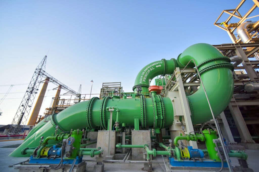 HGIlI1hXoAANst7 - Petróleo y Energía Industrial facility with large green pipelines and pumps outdoors at a plant