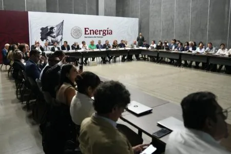 Group of professionals seated around a long U-shaped conference table during a formal meeting, with a large 'Energia' banner in the background.