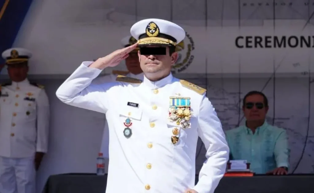 WhatsApp-Image-2025-11-06-at-102819-AM - Petróleo y Energía A naval officer in a white dress uniform saluting, wearing medals and a peaked cap at a ceremony stage.