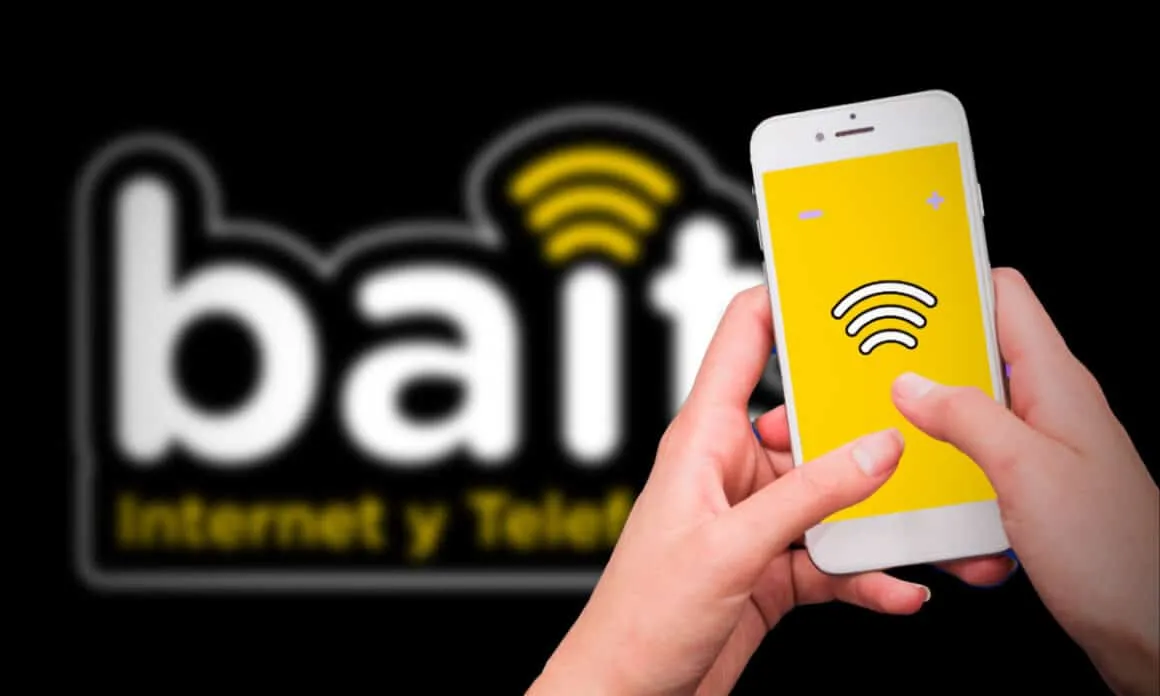 Hands hold a smartphone with a yellow screen showing a wifi symbol on a dark background and blurred logo behind it.