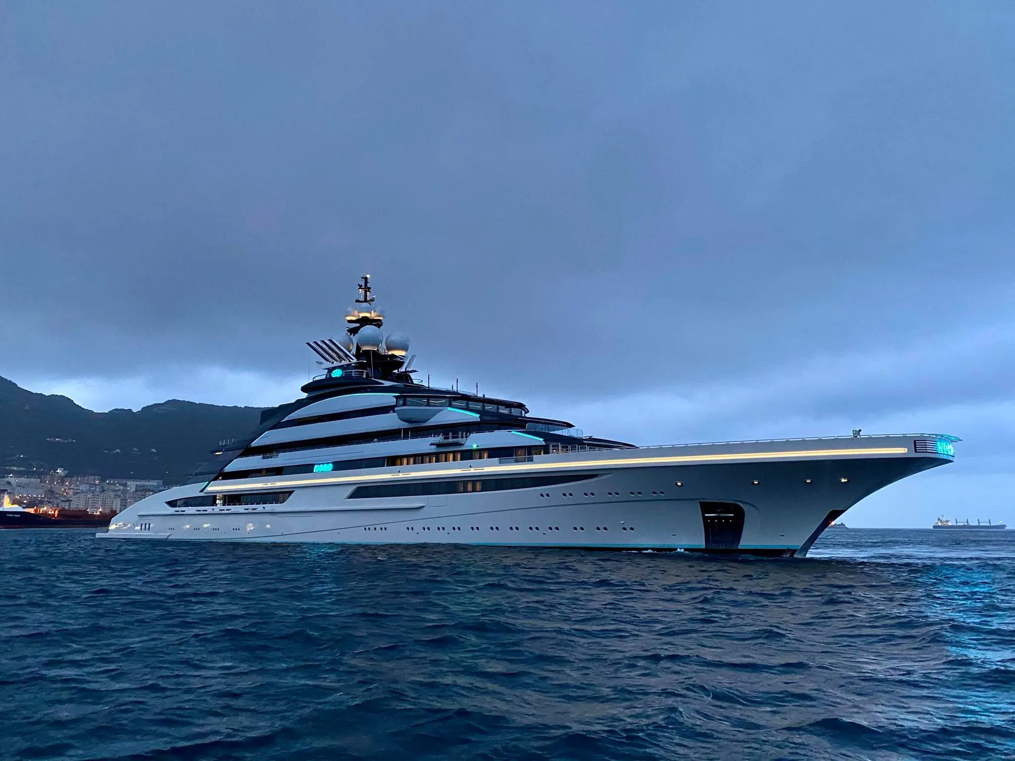 Large white luxury yacht on the water with distant mountains in the background.