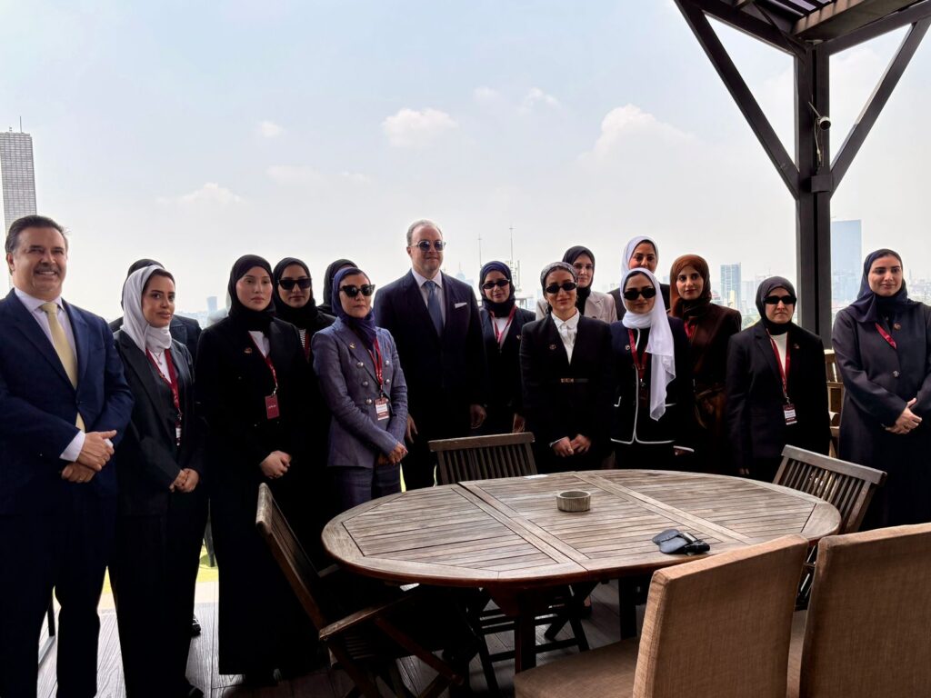 4e2f4ad8-6e16-4f17-8db7-72b313806f4a - Petróleo y Energía Group of professionals in business attire posing on an outdoor terrace with a city skyline in the background