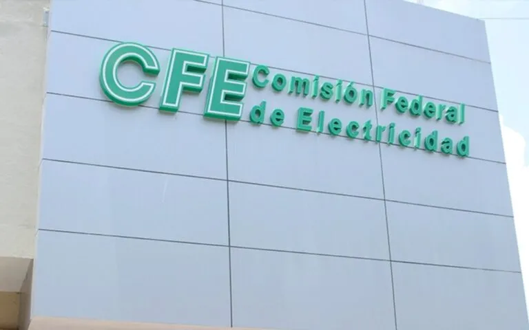Green CFE sign reading 'Comisión Federal de Electricidad' on a blue-gray tiled building facade