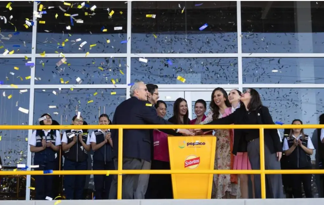 Group of people celebrate a grand opening on a balcony, confetti raining down and a yellow podium with Sabritas and PepsiCo branding visible in the foreground.