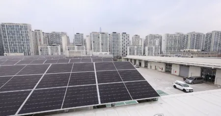 Rooftop solar panels on a flat roof with a city skyline of high-rise buildings in the distance.