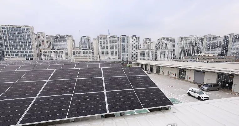 Rooftop solar panels on a flat roof with a city skyline of high-rise buildings in the distance.