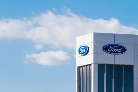 Exterior of a modern building with Ford logos on the facade against a blue sky.