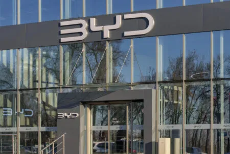 Modern glass-fronted office building with a dark gray band and large BYD lettering on the facade.