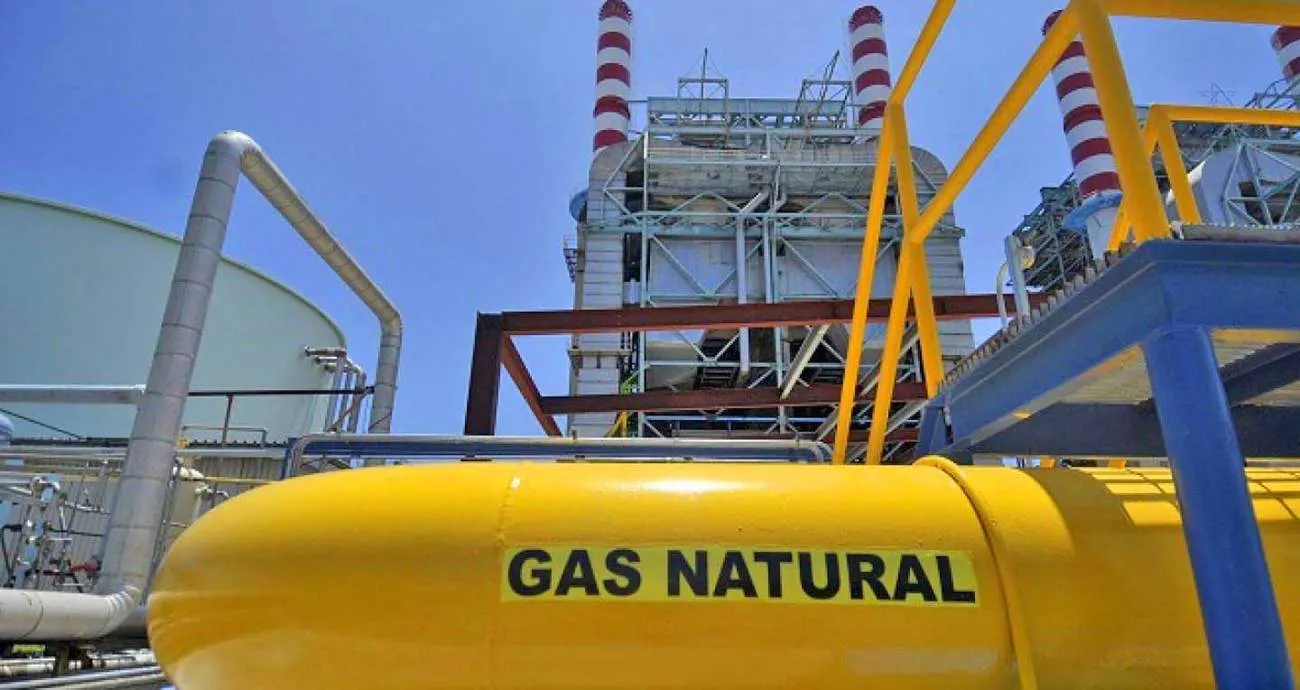 Yellow natural gas pipeline at an industrial plant with metal scaffolding and a blue sky above.