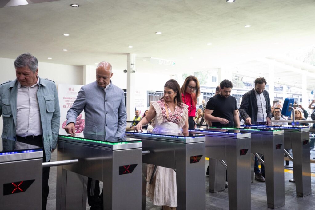 HID1A42XwAAd5Xz - Petróleo y Energía Group of people passing through metal turnstiles with red X indicators at a security checkpoint in a bright, modern indoor space.