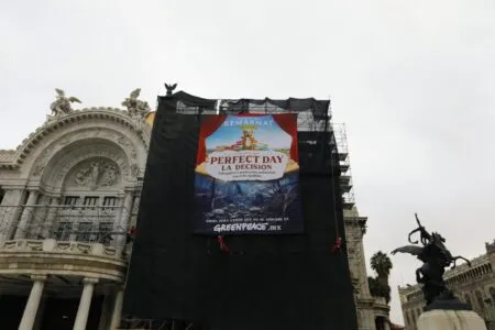 Large vertical banner on a historic building reads 'PERFECT DAY LA DECISIÓN' with Greenpeace MX at the bottom, flanked by scaffolding.