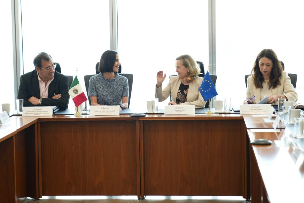 HJWNgEVWIAAQWel - Petróleo y Energía Four officials sit at a long conference table in a bright room, with Mexican and European Union flags shown on the table in front of them.