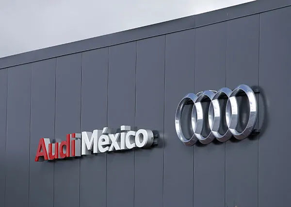 Audi México storefront sign on a dark grey wall with the silver four-ring Audi logo to the right.