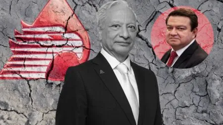 Two men in suits stand in front of a cracked gray wall with a large red emblem on the left and a circular inset portrait of a second man on the right behind them.