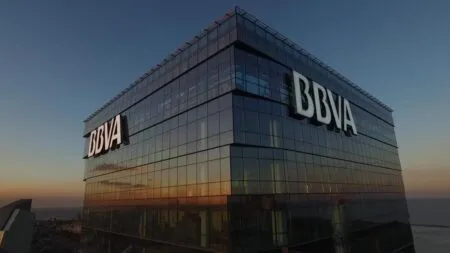 Glass corporate tower with BBVA logo, reflecting sunset over the city