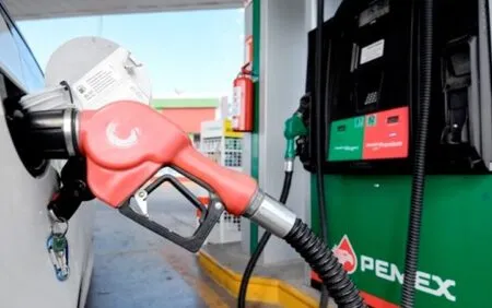 Red fuel nozzle connected to a car at a Pemex gas station.