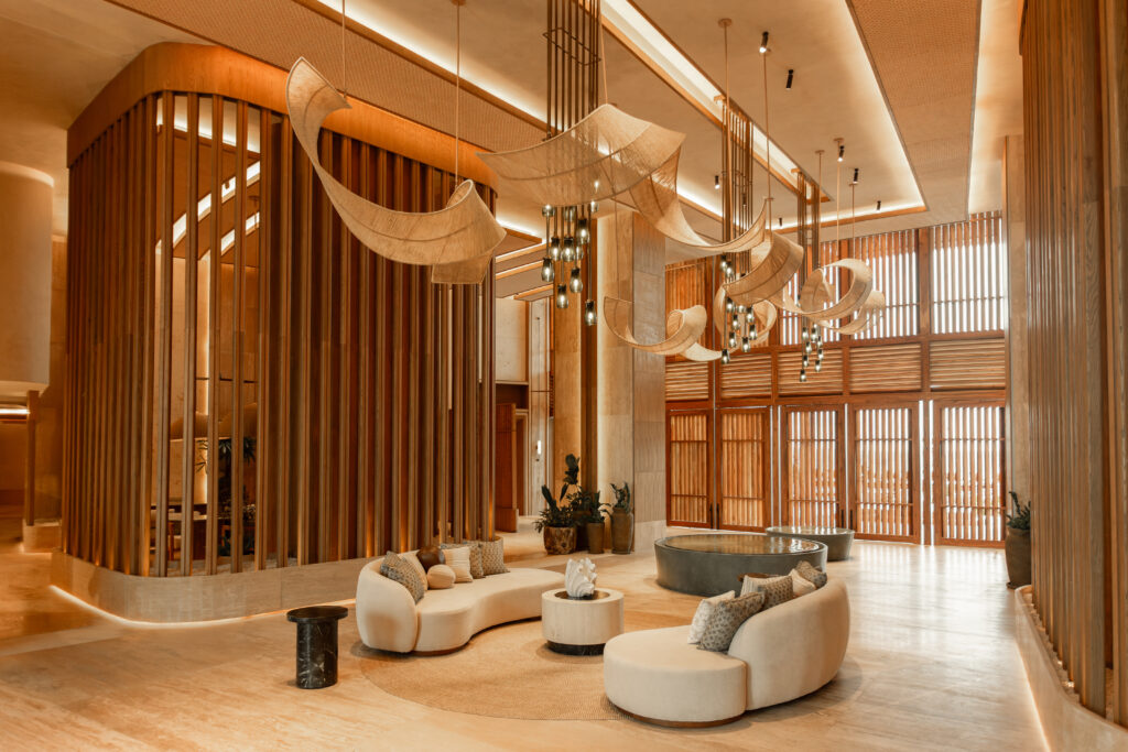 03 - Petróleo y Energía Hotel lobby with warm wood lattice walls, curved fabric light fixtures, and circular beige seating area