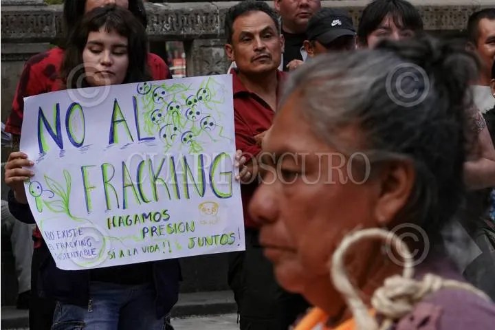 Crowd of protesters, including a person holding a sign that reads 'NO AL FRACKING' against fracking.