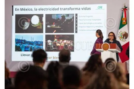 Conference scene with a presenter at a podium beside a large slide titled 'En México, la electricidad transforma vidas', showing four image thumbnails and bullet points, audience in foreground, and a Mexican flag nearby.