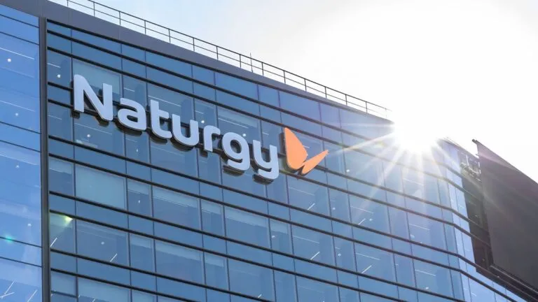 Naturgy logo on a blue glass office building with sunlight glare nearby
