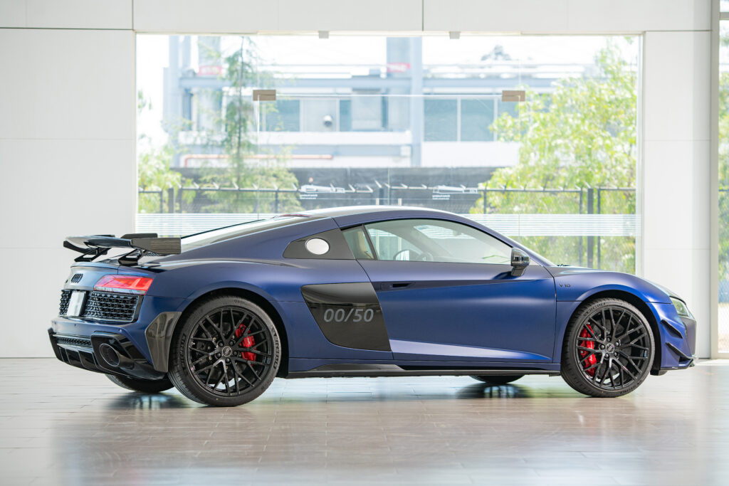 wwwalexbertheaucom - Petróleo y Energía Blue Audi R8 sports car on display in a bright showroom, side view with black wheels and red brake calipers.