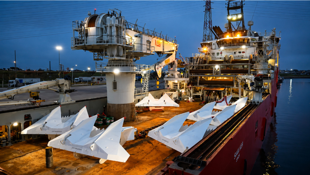 Captura de pantalla 2026-06-16 132646 - Petróleo y Energía Large crane-equipped offshore support vessel at dusk with white wedge‑shaped modules stacked on its deck.