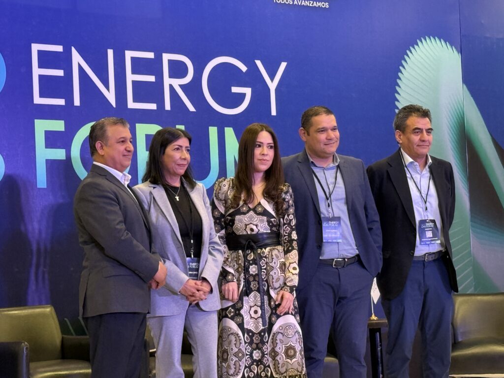 IMG_4432 - Petróleo y Energía Five professionals in business attire posing for a photo at an energy forum, blue backdrop with large ENERGY text.