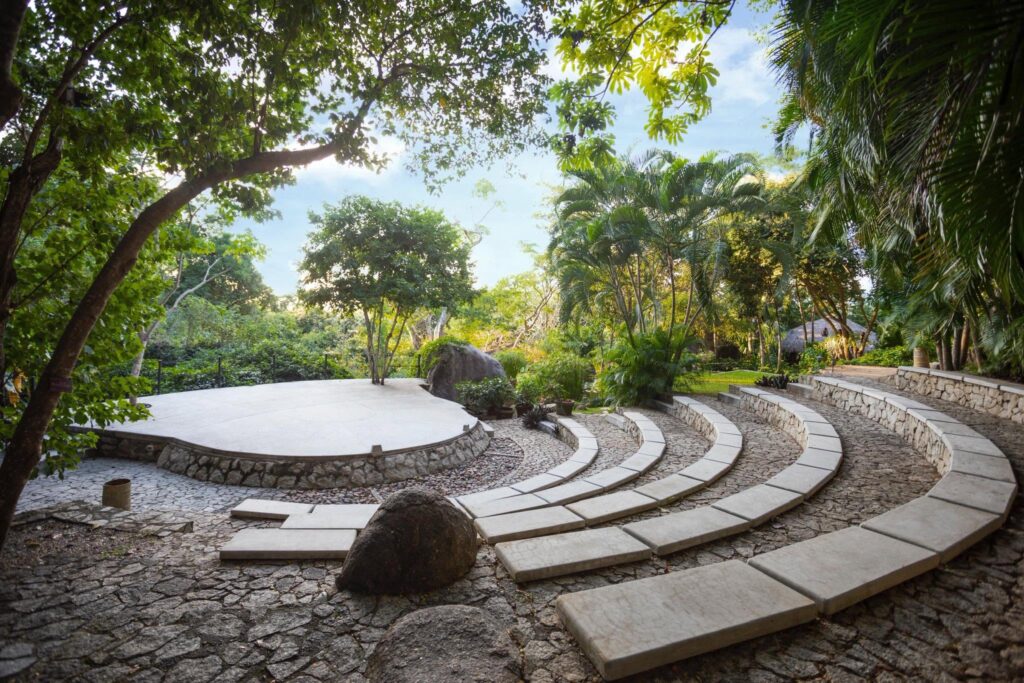 Jardín Botánico de Acapulco Esther Pliego de Salinas 5 - Petróleo y Energía Stone semicircular seating terrace in a tropical garden, surrounded by palm trees and greenery.