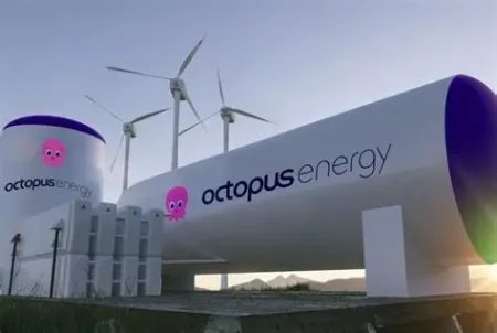 Huge white pipeline branded 'octopus energy' with a pink octopus logo and wind turbines in the background.