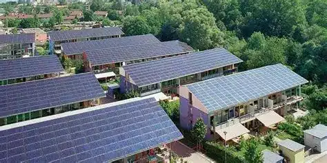 Aerial view of a residential neighborhood with solar panels installed on most roof surfaces amid trees and greenery.