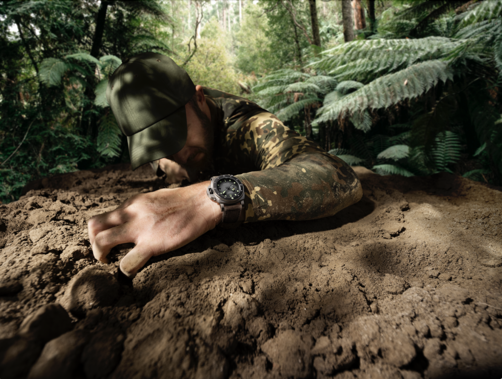 PANERAI 4 - Petróleo y Energía Soldier in camouflage shirt and cap digging a trench in a forest, with a steel Panerai watch visible on the wrist.