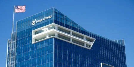 Sleek glass office tower with a white inset architectural feature, Sempre Energy logo, and an American flag at the top.