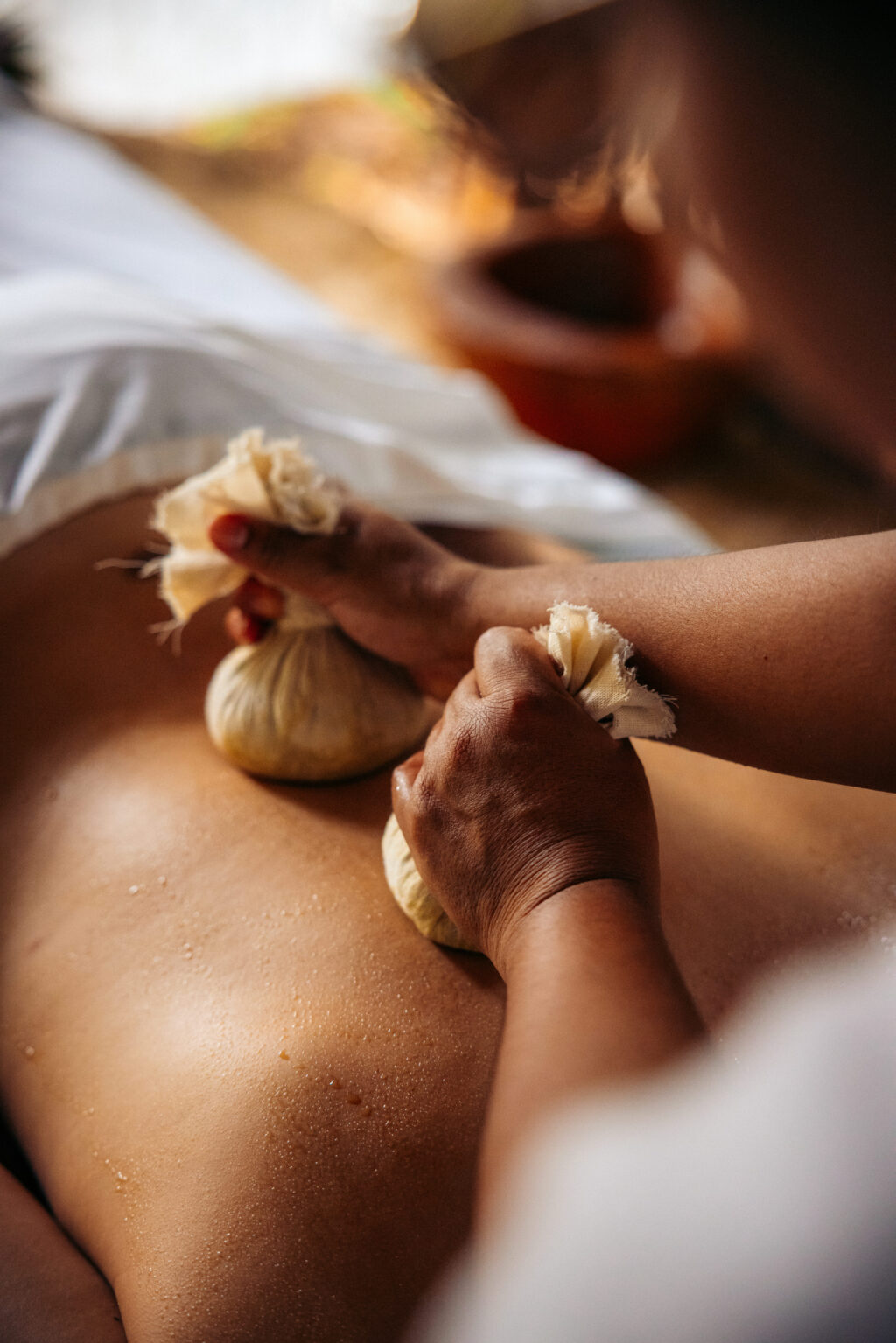 VRM63 - Petróleo y Energía Close-up of two hands peeling garlic bulbs over a bare arm, with a blurred background.