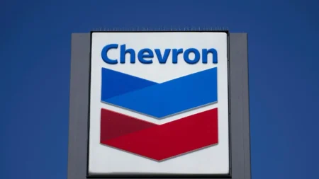 Chevron gas station sign with blue and red chevron shapes against a clear blue sky, the word 'Chevron' at the top.
