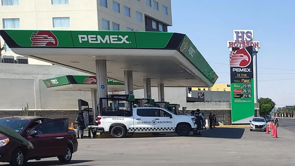 Pemex gas station canopy with a Guardia Nacional pickup and officers near the pumps.
