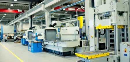 Factory floor with automated machinery and control panels along an assembly line in a well-lit plant.