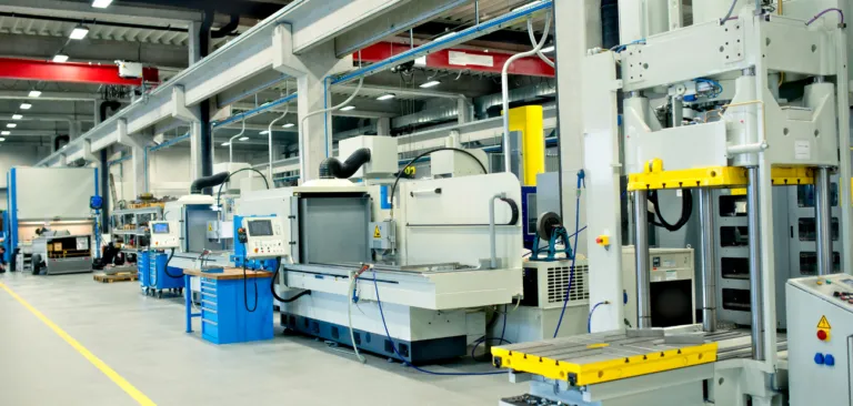Factory floor with automated machinery and control panels along an assembly line in a well-lit plant.