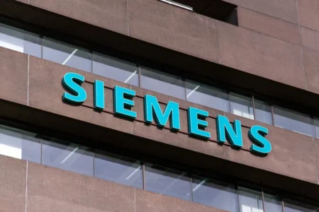 Siemens company sign in turquoise letters on the facade of a brown office building.