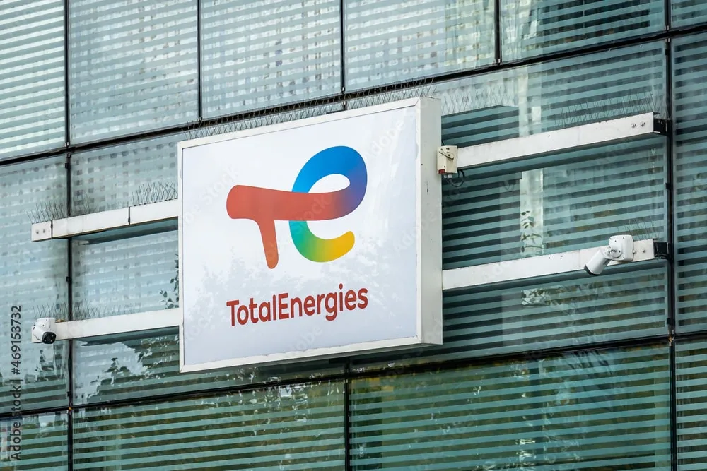 TotalEnergies logo sign mounted on a modern glass building façade.