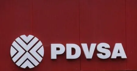 PDVSA logo with circular emblem and bold PDVSA text on a red background wall.