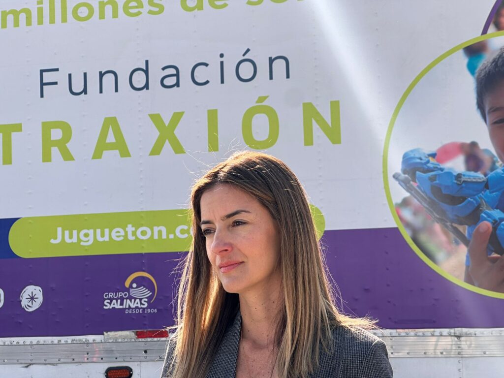 Alejandra Méndez_Fundación - Petróleo y Energía Woman stands in front of a large banner/trailer with Spanish text reading 'Fundación TRAXIÓN' and 'Jugueton.com'.
