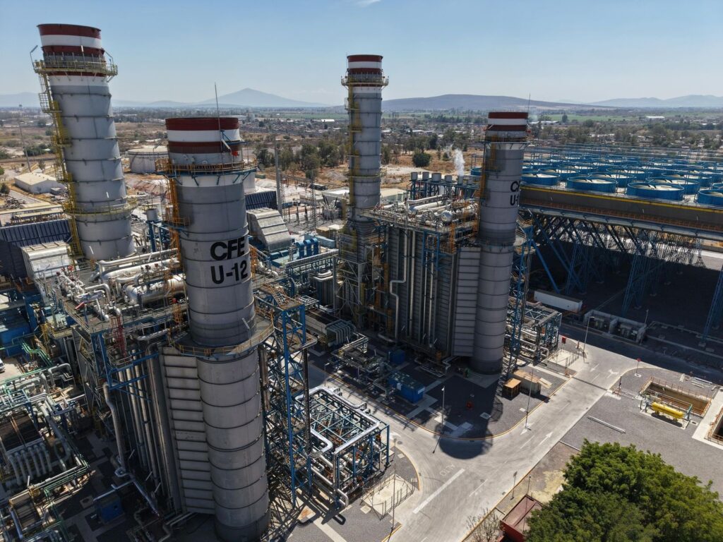 A large chemical processing refinery with tall distillation columns, networks of pipes and platforms, under a clear sky.