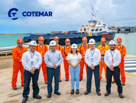 Group photo of Cotemar team wearing orange coveralls and white helmets at a port, with a tugboat in the background.