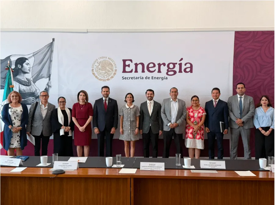 Group of officials in formal attire posing for a photo in front of an Energia banner with the Mexican seal and flag on the left.