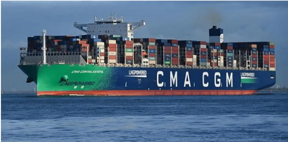 Large cargo container ship on calm water, stacked with colorful shipping containers, CMA CGM branding visible along the hull.