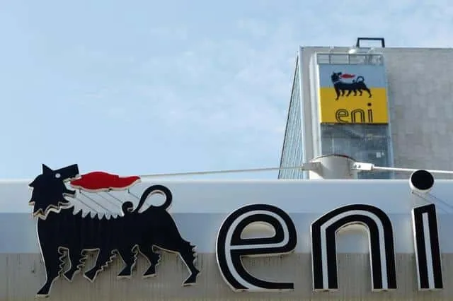 Close-up of an ENI sign featuring the six-legged dog logo and bold 'eni' lettering against a blue sky.