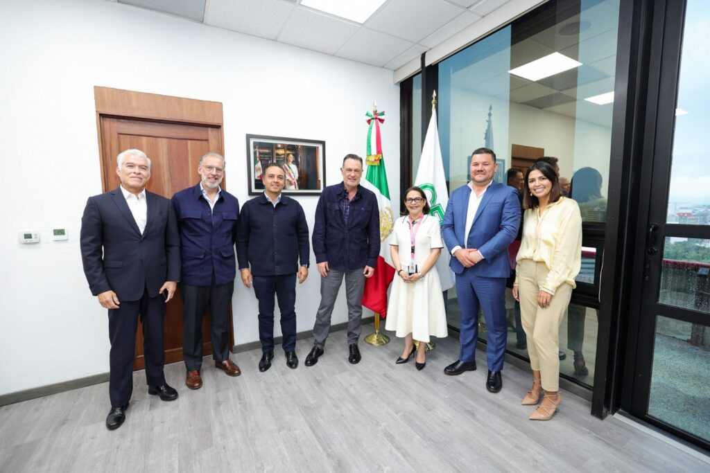 HNJ04eiW4AA36dg - Petróleo y Energía Seven professionals stand in an office lobby beside a Mexican flag and another banner behind them.